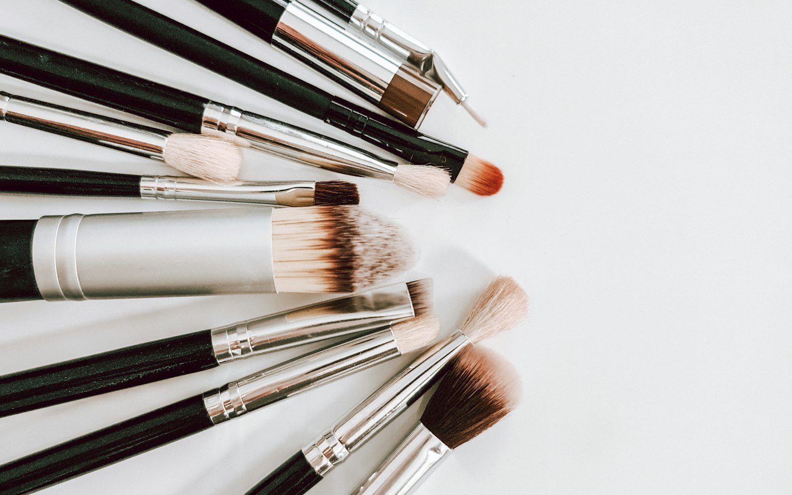 Makeup brushes of various sizes arranged on a white surface